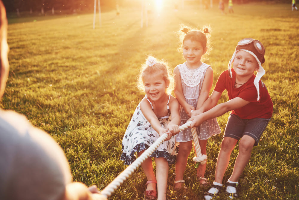 children-play-with-dad-in-the-park-they-pull-the-rope-and-have-fun-laying-on-sunny-day (1)