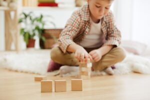 little-child-sitting-on-the-floor-pretty-boy-palying-with-wooden-cubes-at-home-conceptual-image-with-copy-or-negative-space-and-mock-up-for-your-text (1)