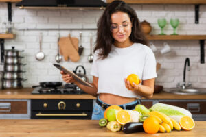 medium-shot-woman-with-tablet-looking-at-an-orange (1)